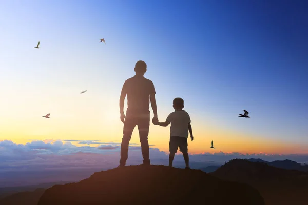 Отец и сын держатся за руки на восходе солнца . — стоковое фото