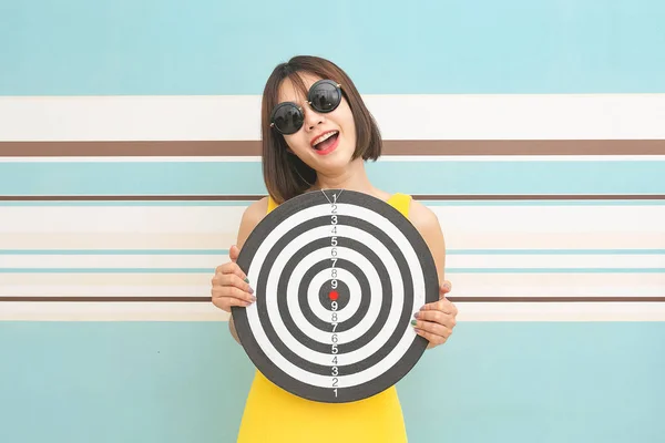 Goals concept with young woman holding target on blue background