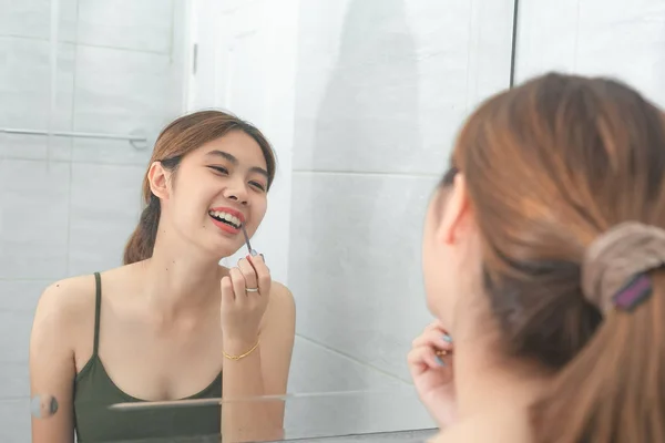 Asiático mujeres felicidad maquillaje por rojo lápiz labial con espejo en baño —  Fotos de Stock