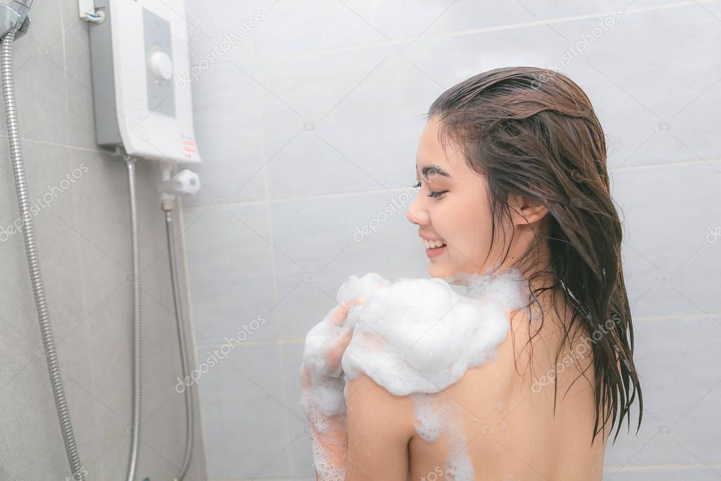 Woman taking a shower enjoying foam on her shoulder.
