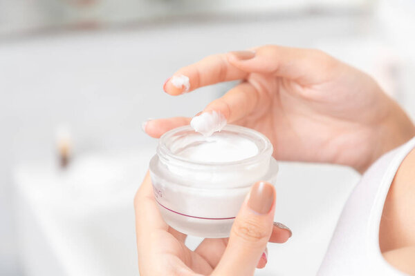 Женщина держит в руке увлажняющий крем, кожу и морщины от загрязнений..