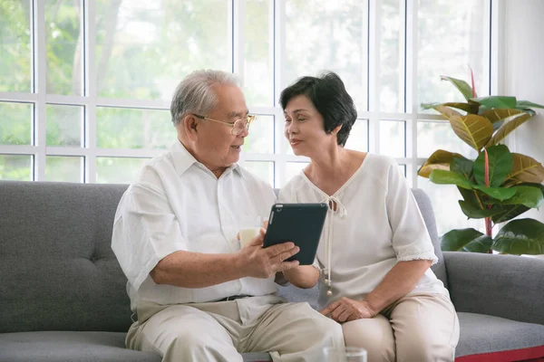 Couple Seniors Smiling Looking Same Tablet Sofa — Stock Photo, Image