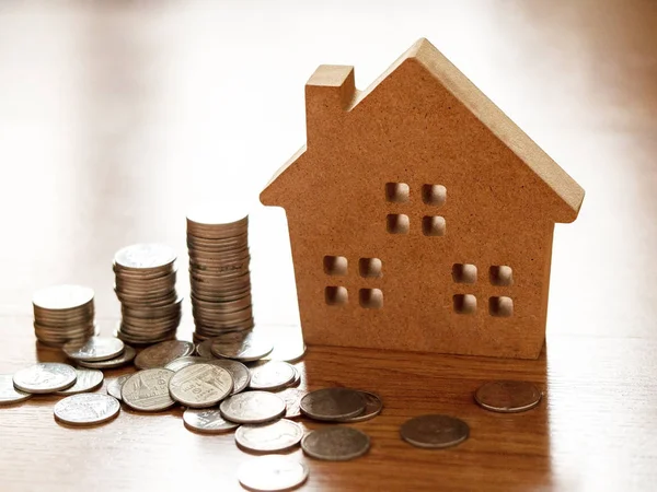 住宅ローン住宅や不動産を売買する ビジネスコンセプトは 家庭のためのお金を節約します コイン付き茶色の木製のホームモデル — ストック写真