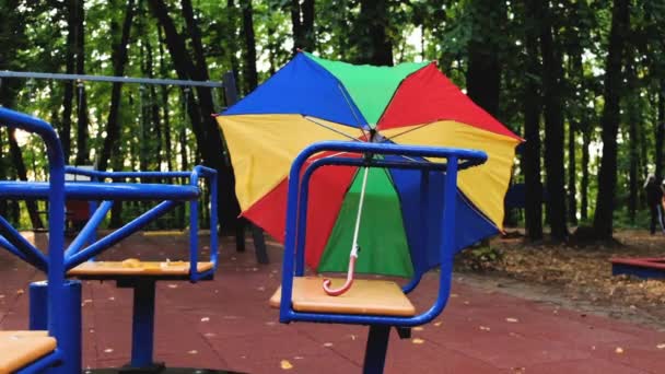 カルーセルカルーセルは 秋に空の遊び場で色の傘を持って回転します スローモーション 4Kビデオ — ストック動画
