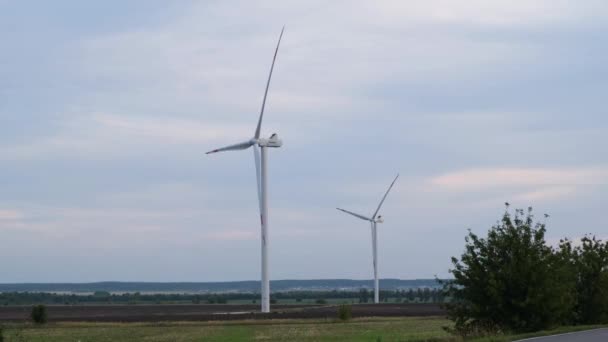 グリーンフィールドにおける風力タービンの発電の航空写真 回転風力タービンのクローズアップ ウィンドファームドローン映像 風の強い天候で回転する風力発電所のタービン — ストック動画