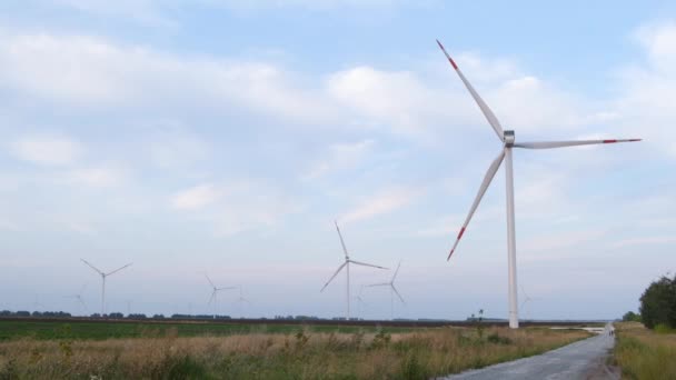 グリーンフィールドにおける風力タービンの発電の航空写真。回転風力タービンのクローズアップ。ウィンドファームドローン映像。風の強い天候で回転する風力発電所のタービン. — ストック動画