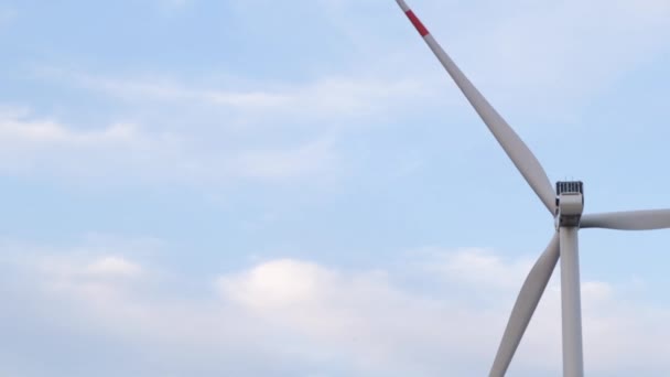 Widok z lotu ptaka elektryczności generującej turbiny wiatrowej w zielonej dziedzinie. Zbliżenie obrotowej turbiny wiatrowej. Materiał Dronowy farmy wiatrowej. Turbiny w farm wiatrowych obracanie w wietrzne Pogoda. — Wideo stockowe