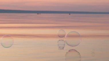 Gün batımında suyun üzerinde uçan kabarcıklar. Anti-stres video. Soyut video.