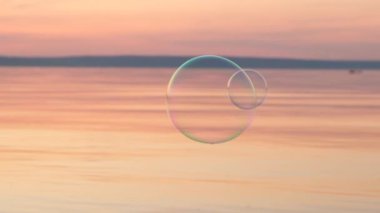 Gün batımında suyun üzerinde uçan kabarcıklar. Anti-stres video. Soyut video.