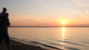 Mutlu baba ve kızı gün batımında sahilde oynarken