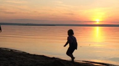 Mutlu baba ve kızı gün batımında sahilde oynarken