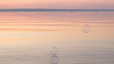 Gün batımında suyun üzerinde uçan kabarcıklar. Anti-stres video. Soyut video.