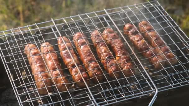 Primo piano di salsicce su una piccola griglia barbecue . — Video Stock