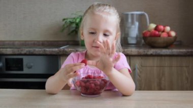 Sevimli küçük çocuk kız portre komik yeme kırmızı ahududu parmaklarına koydu