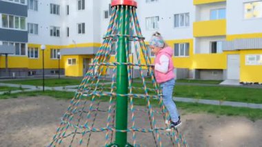 Mutlu kız oyun alanında oynuyor, eğleniyor. Yavaş çekim. Neşeli aktif çocukluk.