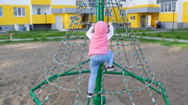 Mutlu kız oyun alanında oynuyor, eğleniyor. Yavaş çekim. Neşeli aktif çocukluk.