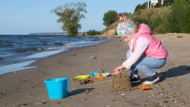 可爱的小女孩在沙滩上玩慢动作 沿着海滩散步的小女孩小女孩在海边独自慢慢地走着 孩子在沙滩上的海浪上散步 — 图库视频影像