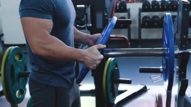 Ellerde Yakın Çekim: Bodybuilder Bir Barbell Ek Ağırlıklar koyar. Kas Fit İnsanlar Eğitim, Egzersiz, Hardcore Garage Spor Salonu Tesisi Ağır Ağırlık Kaldırma