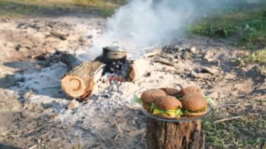 Temiz havada bir kamp ateşi arka planda Lezzetli ev yapımı Burger. 4k video.