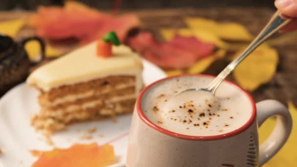 Herbstliche Komposition mit Cappuccino, Karottenkuchen, Kürbis und Blättern auf einem alten Holztisch. Herbstkonzept. — Stockvideo