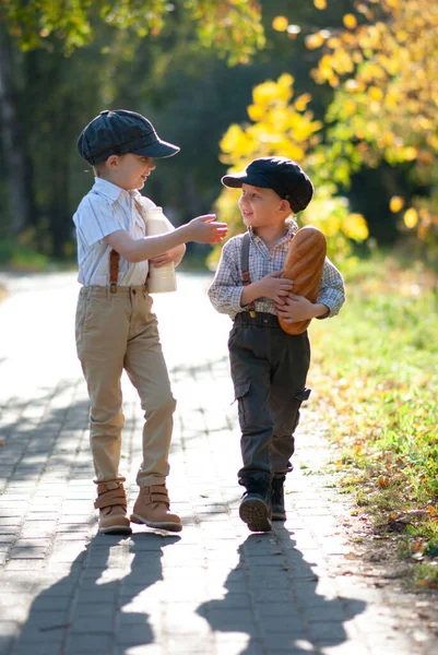 Köylü çocuklar bir şişe süt ve kolunun altında somunla yol boyunca yürüyorlar.