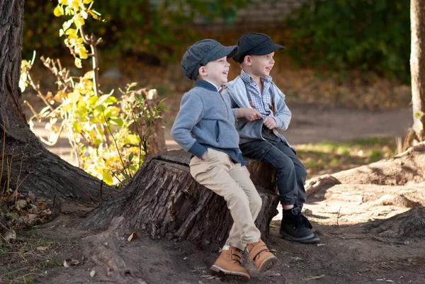 Köy çocukları ağaç kütüğünde otururken gülerler.