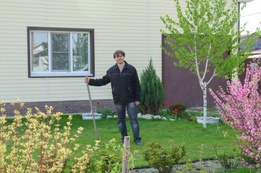 Bir adam yazlık evinde yeşil çimenlik üzerinde eski yeşillik tırmıklar