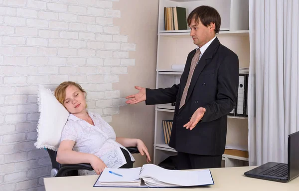 A pregnant office employee sleeps in the workplace, and the boss stands nearby and spreads her arms