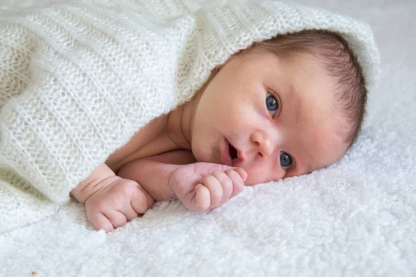 Neugeborenes liegt auf weißem Plaid, bedeckt mit einem gestrickten Schal — Stockfoto