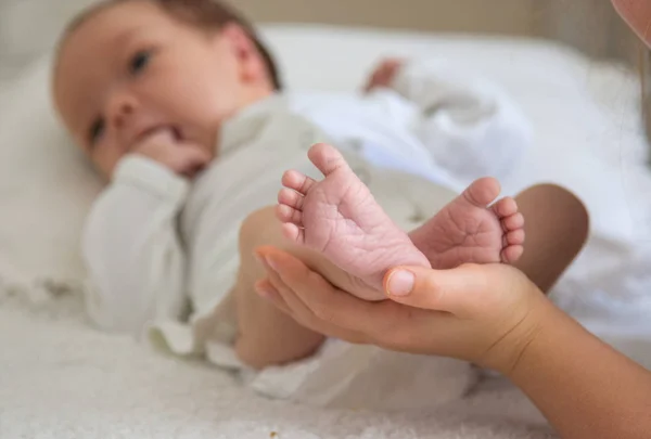 A kezek az újszülött lábát tartsuk — Stock Fotó