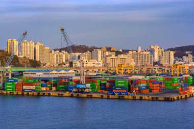 Busan, Güney Kore - 21 Ocak 2017: Sunset Busan, arka planda konteyner terminali şehir manzarası ile yaktı.