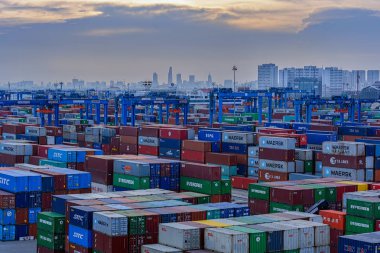 HO CHI MINH CITY (SAIGON), VIETNAM - Mar 29, 2017: Colorful shipping containers are stacked at the Saigon Newport Corporation (SNP) container terminal with city skyline on the background. clipart
