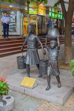 Busan, Güney Kore - Eyl 04, 2017: bir 40 adımları kültür ve Turizm Tema sokakta su taşıyan çocuk tasvir pirinç heykel serisi.