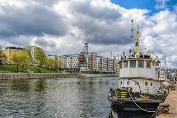 Vintage boats moored at Hammarby canal embankment in front of waterfront apartment buildings at sunny spring day. Stockholm, Sweden. — Stock Photo, Image