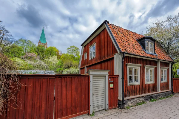 Typiskt svenskt bostadshus målat i traditionell Falun röd med trästängsel mot Sofia kyrkan i bakgrunden i Vitabergsparken, Stockholm. — Stockfoto