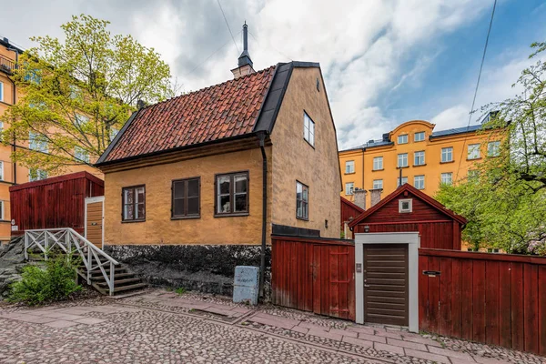 Smal kullerstensbelagd gata i ett historiskt område på Asoberget med ett trähus målat i traditionell Falun röd. — Stockfoto