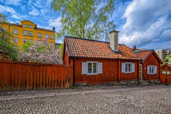 Smal kullerstensbelagd gata i ett historiskt område på Asoberget med ett trähus målat i traditionell Falun röd. — Stockfoto