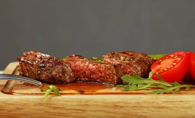 Yeşil kuşkonmaz ve domates ahşap kesme tahtası, düşük açılı görünümü üzerinde bir ızgara kavrulmuş Dana biftek kadar kapatın