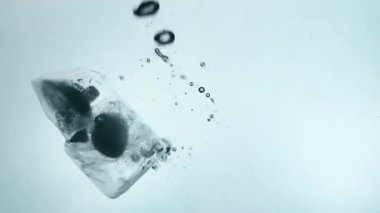 Buz küpleri görünür düştü temizleyin ve hava kabarcıkları ile float ve mavi şeffaf su içerisinde aşırı yakın düşük açılı yan görünüm, ağır çekim, erime