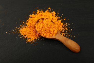 Sarı zerdeçal tozu baharat siyah arduvaz kurulu, yüksek açılı görünüş arka plan üzerinde tam bir tahta kaşık kaşık kadar kapatın