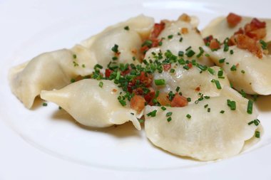 Pierogi veya doldurulmuş varenyky tabak köfte pastırma patates cipsi ile dolu ve yeşil bıçaklamak soğan, geleneksel Doğu Avrupa mutfağı yemek popüler Polonya, Ukrayna, Slovakya ve Rusya, kapatın, yüksek açılı görünüş