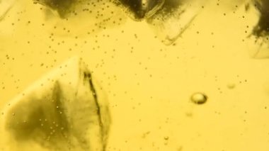 Aşırı yakın çekim köpüklü şarap, soda su veya buz cam ile limonata, bırakılan, düşük açılı yan görünüş, ağır çekim bir buz küpü düşer