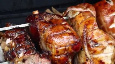 Birkaç büyük domuz jambonu parçasını kapatın. Açık ahşap şömine şiş ve yüksek açılı görüşte kavrulmak üzere dönsün.