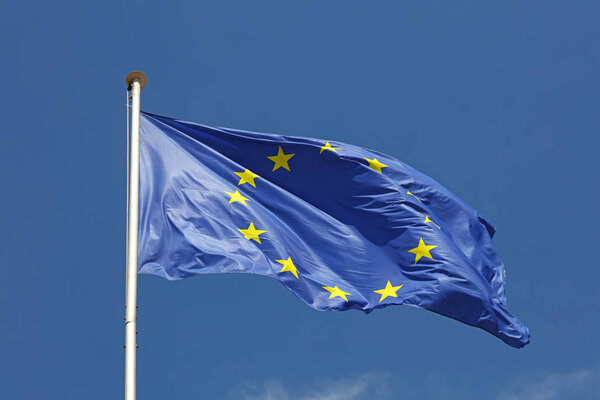 Close up flag of EU, European Union waving and blowing in the wind over blue sky, low angle view