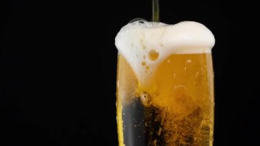 Arka plan dökme lager bira kabarcıkları ile yukarı ve cam siyah arka plan üzerinde köpük, bantlayın kapatıp, akan üst, düşük açılı yan görünüm, ağır çekim üzerinde çalıştırın