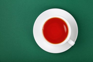 Hemen üstüne siyah kırmızı çay tabağı yeşil tablo arka planda, yükseltilmiş üstten görünüm, bir tam beyaz fincan kadar kapatın