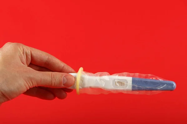 Närbild Kvinna Hand Håller Graviditetstest Med Kondom Den Över Röd — Stockfoto