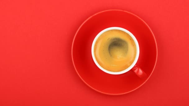 关闭一杯咖啡和飞碟在生动的红色纸背景与慢动作动画动态图片旋转的咖啡泡沫 高架顶部视图 直接高于 — 图库视频影像