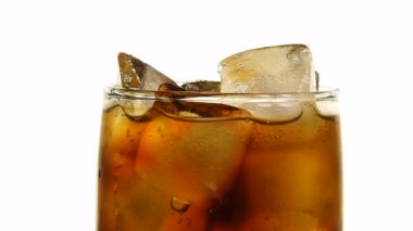 Aşırı yakın çekim gazlı cola meşrubat buz küpleri ile dolu bardak beyaz arka plan, düşük açılı yan görünüm, ağır çekim üzerinde