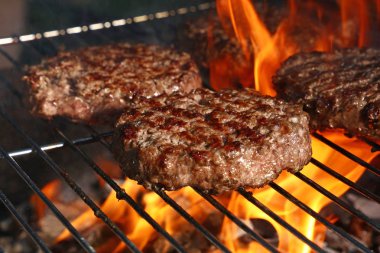Biftek ya da domuz eti barbeküsü hamburgerleri BBC alev ızgarasında kızartılmış, yüksek açı manzaralı.